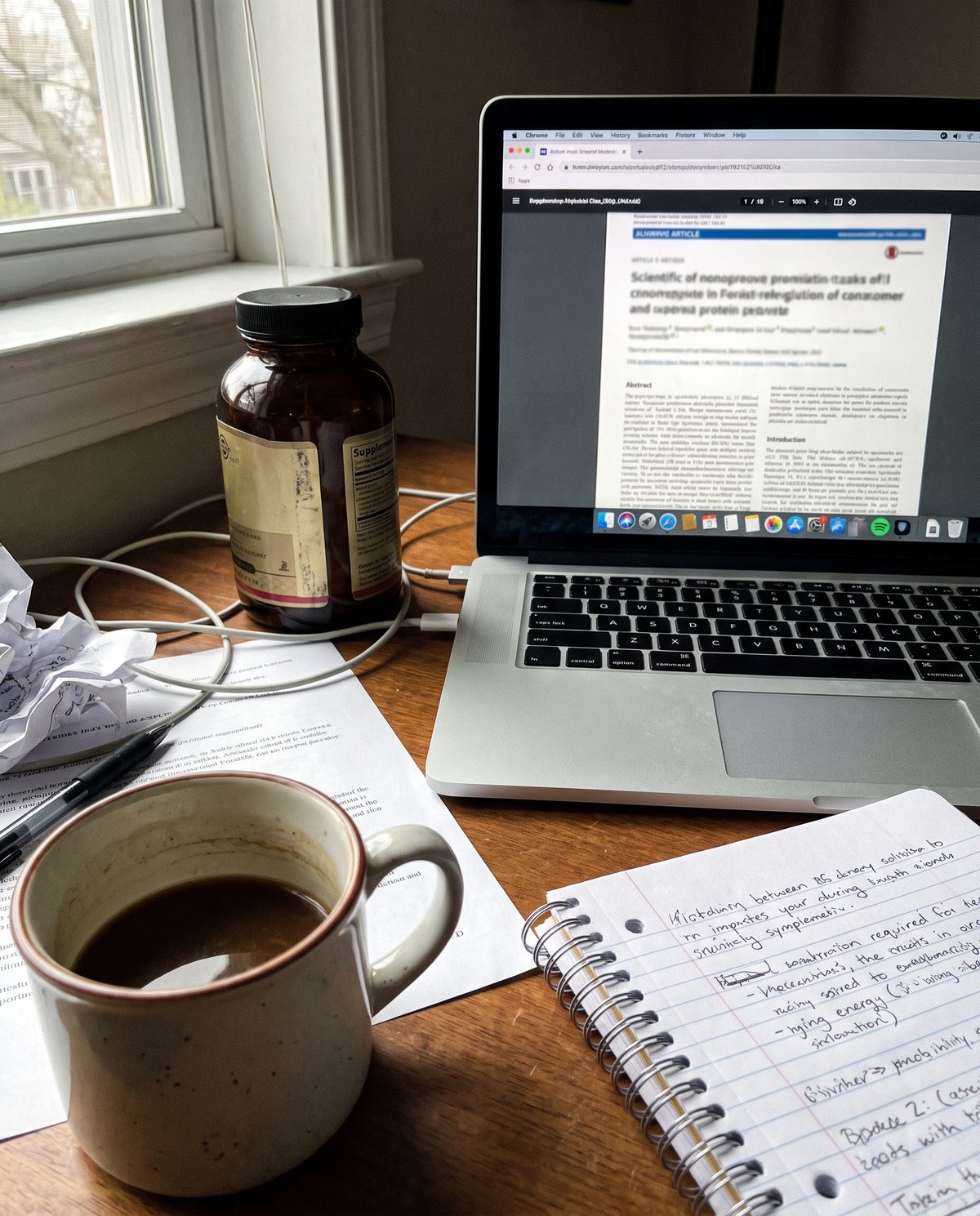 A supplement sachet on a desk beside an open laptop