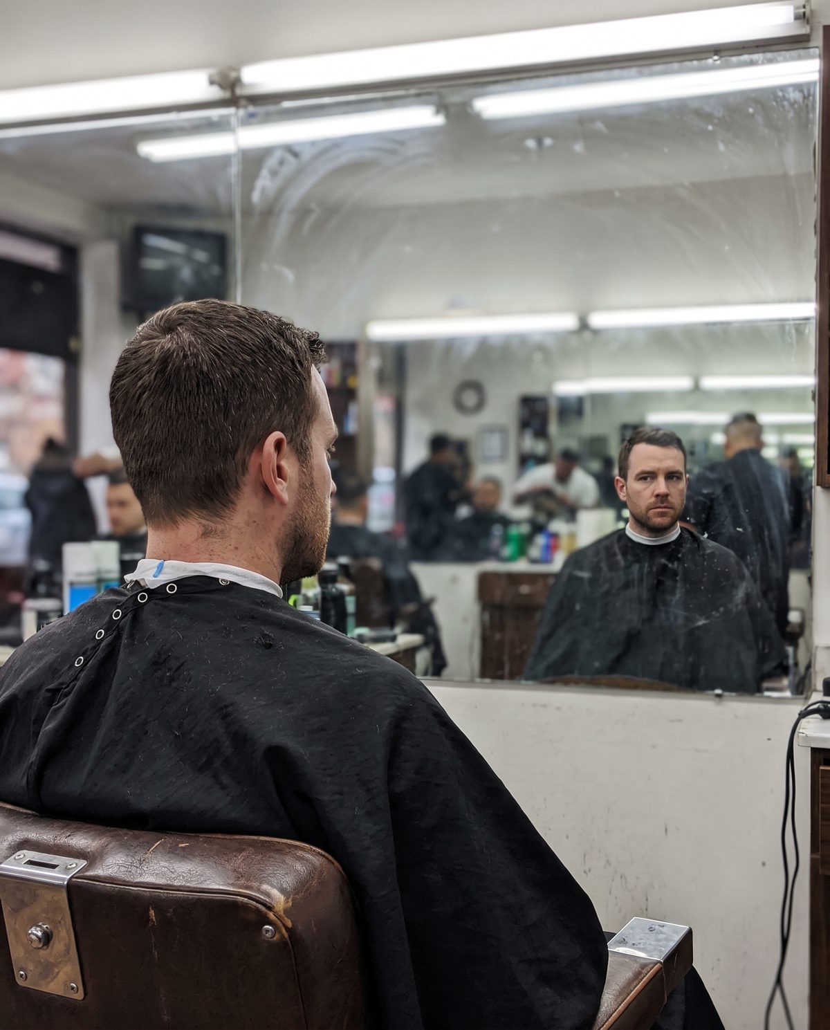 A man in a barber's chair looking at his reflection